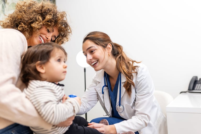 Pediatric checkup. Smiling female doctor in a white coat consulting with a mother and her young child in a clinic, Healthcare and Medicine concept. Friendly pediatrician talking to family patient.